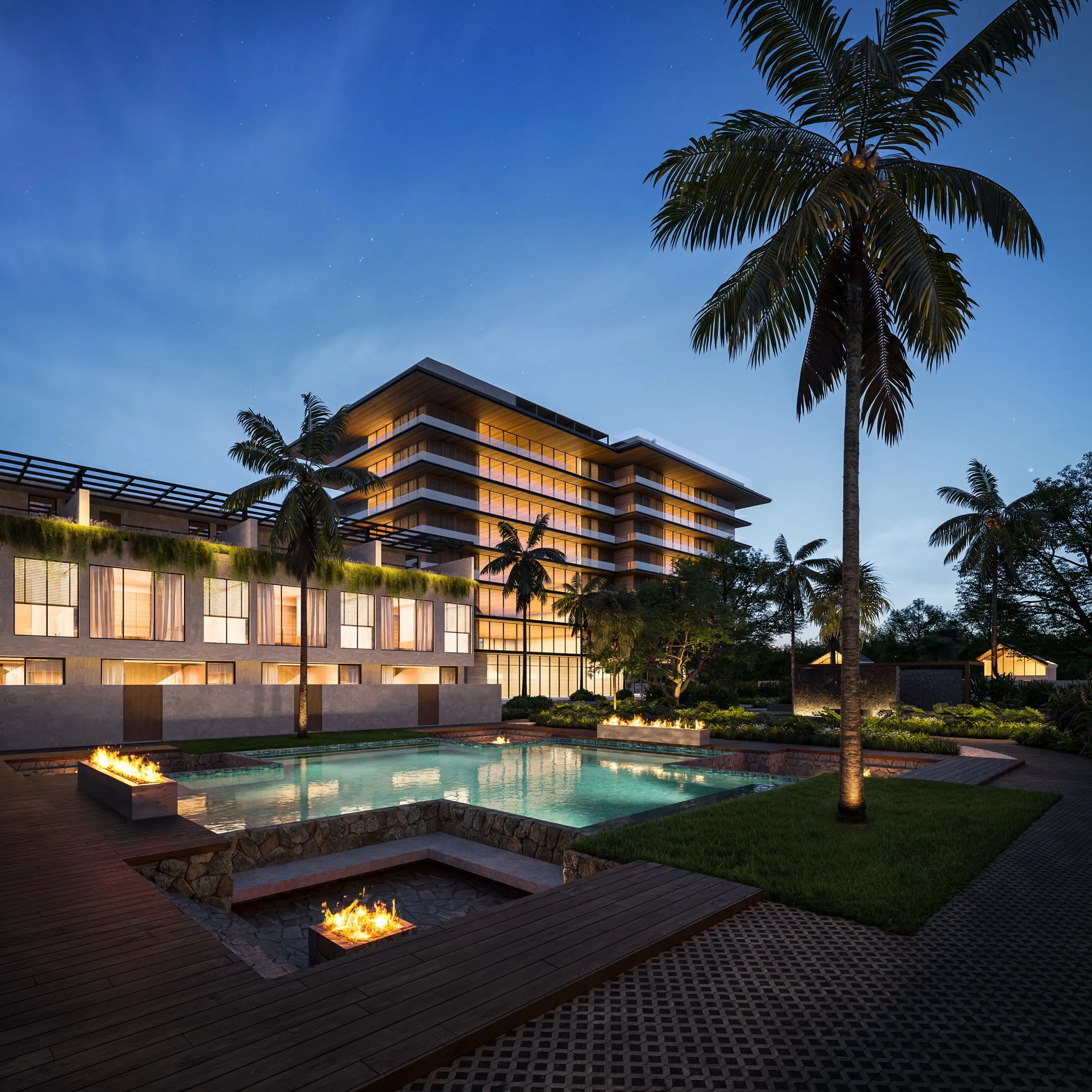 The pool courtyard at night with fire pits lit and the tower glowing behind